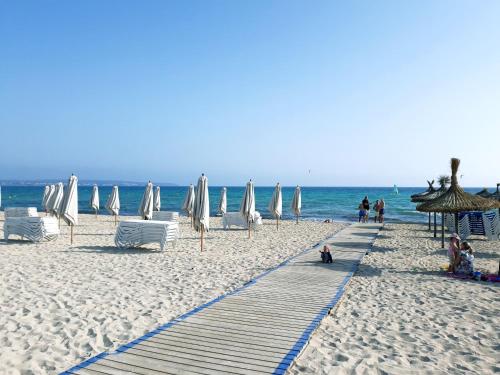 a beach with white umbrellas and chairs and the ocean at Bonito apartamento delante del mar in Can Pastilla