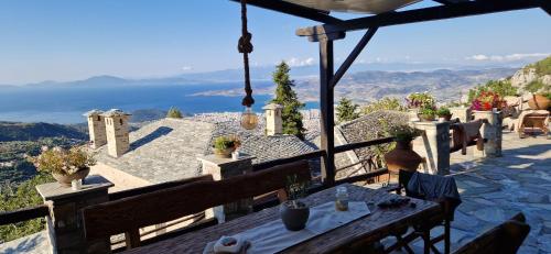 a table on a balcony with a view of the ocean at Archontiko Mansion Porteli Αρχοντικο Πορτελι in Makrinítsa