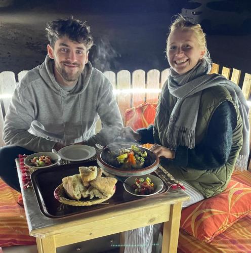 a man and woman sitting at a table with a tray of food at Tildi surf house in Imsouane