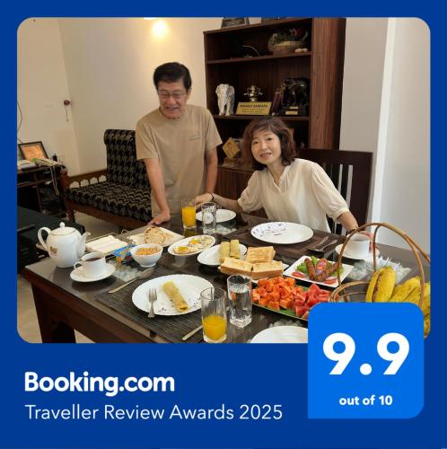 a man and woman sitting at a table with food at Emerald Home Stay in Anuradhapura
