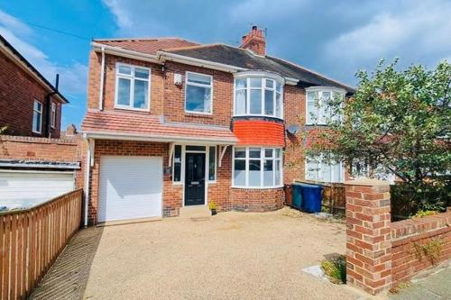 ein Backsteinhaus mit einer weißen Garage in der Unterkunft Elegant 4BR Home: Stylish Comfort Retreat in Derwent Haugh