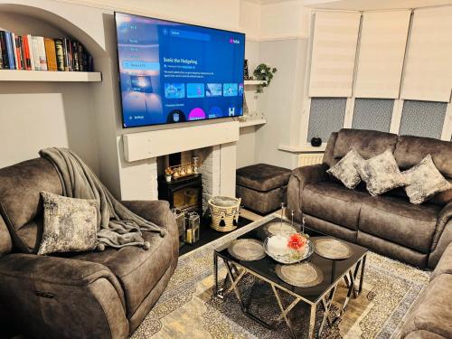 ein Wohnzimmer mit zwei Sofas und einem Flachbildfernseher in der Unterkunft Elegant 4BR Home: Stylish Comfort Retreat in Derwent Haugh