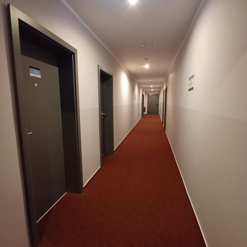 a long hallway with a red carpet and a door at Trip Inn Hotel Düsseldorf Neuss in Neuss