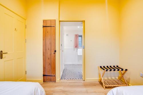 a room with two beds and a door to a bathroom at Charming Coach House Retreat Near Sherborne Abbey in Pointington