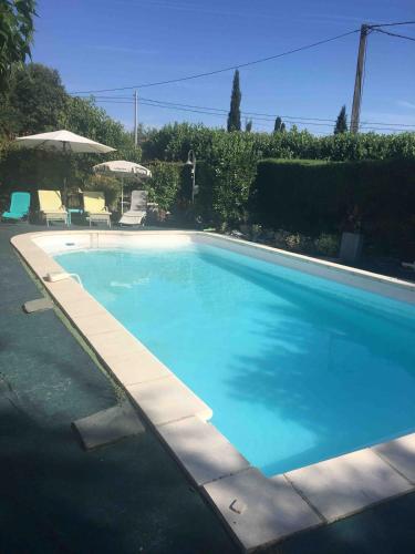 une grande piscine bleue avec des chaises et un parasol dans l'établissement Appartement 3 pièces dans maison en rez-de-jardin, à Peymeinade