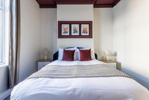 ダーリントンにあるDarlington 4BD Home: Modern Comfort & Free Parkingのベッドルーム(白いベッド、赤い枕付)