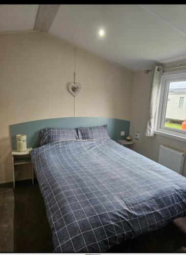 a bedroom with a bed with a blue plaid blanket at Caravan to Hire - CalaGran Fleetwood Blackpool in Fleetwood