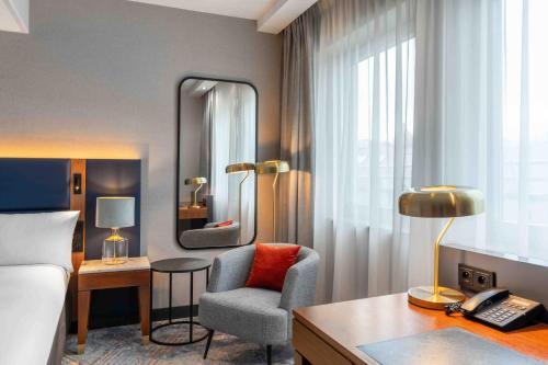 a hotel room with a bed and a chair and a desk at Wyndham Wroclaw Old Town in Wrocław