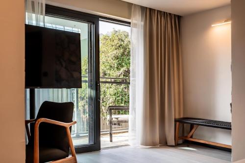 a room with a large window with a chair and a television at Yarden Estate Hotel in Yesod Hamaala