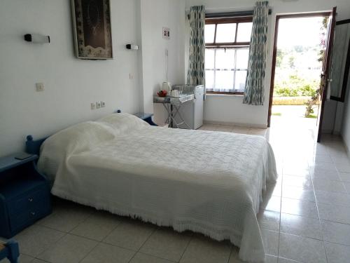a bedroom with a white bed and a window at Dawn's Rooms in Patitiri