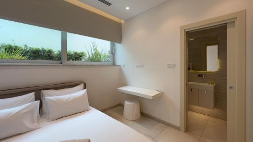 a bedroom with a bed and a sink and a window at Vivo Mare Beachfront Villas - Seashell in Ayia Napa
