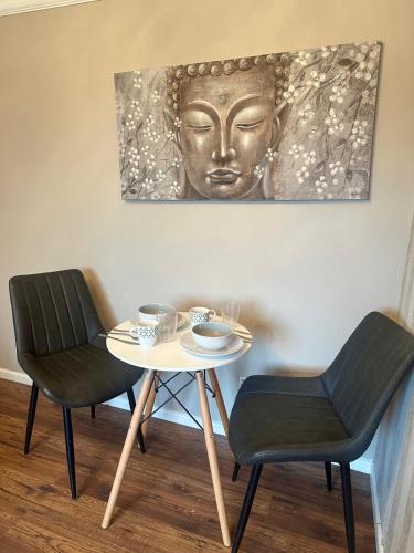 two chairs and a table with a statue on the wall at Comfy One Bedroom Apartment in Darlaston