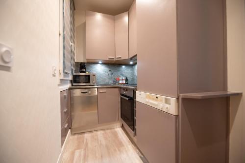une cuisine avec des appareils en acier inoxydable et des armoires blanches dans l'établissement CIA - Trocadéro, cosy & cute flat, à Paris