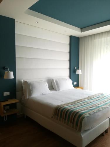 a bedroom with a large white bed with blue walls at Hotel Concord - Nel cuore di Riccione in Riccione