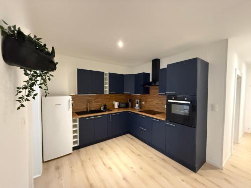 a kitchen with blue cabinets and a white refrigerator at Le Commerce-Gare-Centre-Ville in Montbéliard