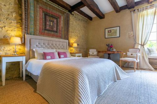 una camera da letto con un grande letto bianco con cuscini rosa di La Maison Louverie a Pontours