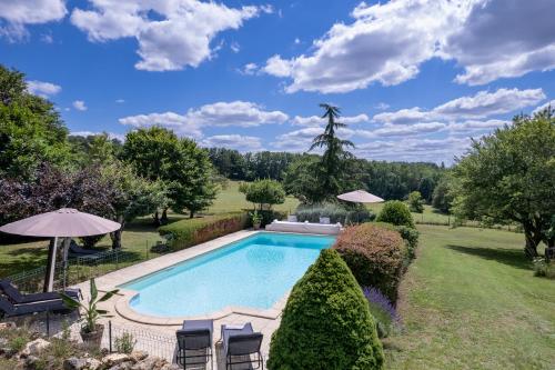 - une piscine dans une cour avec des chaises et des parasols dans l'établissement La Maison Louverie, à Pontours