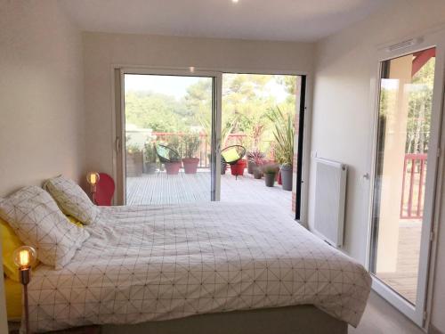 une chambre avec un lit et une porte coulissante en verre dans l'établissement Couleurs Pyla T3 grande terrasse Piscine commune, à La Teste-de-Buch