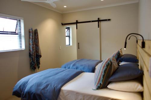 a bedroom with two beds with blue pillows at Ocean Call Inn in Plettenberg Bay