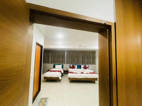 a room with two beds and a mirror at Hotel Coastal Empire in Belgaum