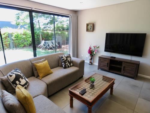 a living room with a couch and a flat screen tv at The Executive - Exclusive Self-Catering Apartments - Ezulwini in Ezulwini