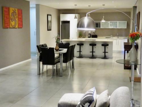 a kitchen and living room with a table and chairs at The Executive - Exclusive Self-Catering Apartments - Ezulwini in Ezulwini