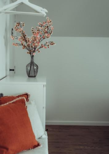 a vase with flowers on a wall next to a bed at Arrivée - 5-Star Luxury Sports-Inspired Holiday House in Merelbeke