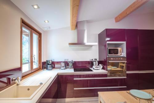 une grande cuisine avec des armoires violettes et un évier dans l'établissement L'Ecrin du Val d'Arly - Vue montagne parking privé, à Flumet