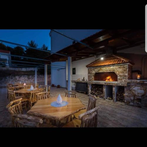 a patio with wooden tables and a large fireplace at La Perla Apartments 2 in Sutivan
