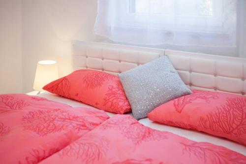 a bed with pink and grey pillows and a window at La Perla Apartments 2 in Sutivan