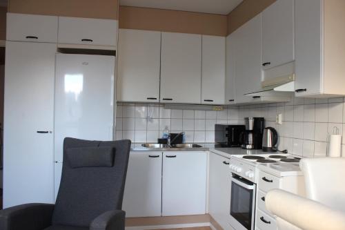 a kitchen with white cabinets and a chair in it at Two-room apartment in the center of Helsinki with a sauna! Free parking! in Helsinki