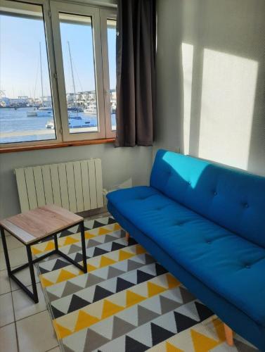 - un canapé bleu dans une chambre avec une table et des fenêtres dans l'établissement Très bel appartement avec vue d'exception & parking, à La Rochelle