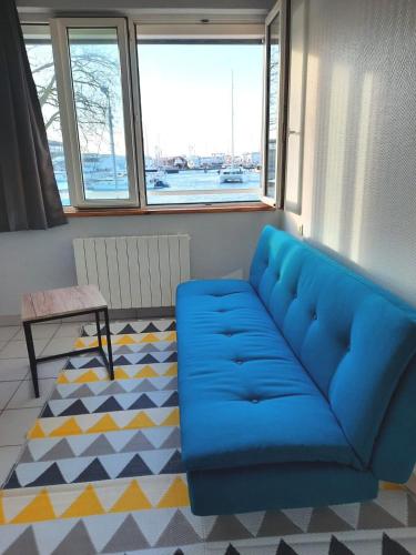 - un canapé bleu dans une pièce avec fenêtres dans l'établissement Très bel appartement avec vue d'exception & parking, à La Rochelle