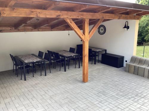 a covered patio with tables and chairs and a clock at Apartmány Ořechovka Wellness in Turnov
