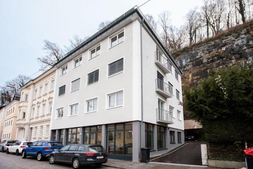 a white building with cars parked in front of it at Magazin Rooms in Salzburg