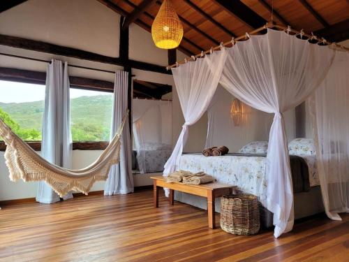 a bedroom with a bed with curtains and a hammock at Vila Santiago - Chalé Quaresmeira in Santana do Riacho