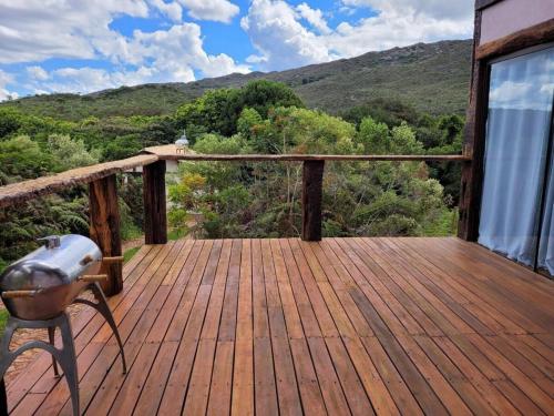a wooden deck with a chair and a view of the mountains at Vila Santiago - Chalé Quaresmeira in Santana do Riacho