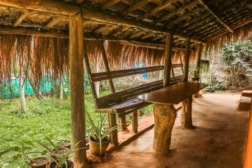 a bench sitting inside of a hut with plants at The Soul Marayoor Mudhouse - Munnar in Marayoor
