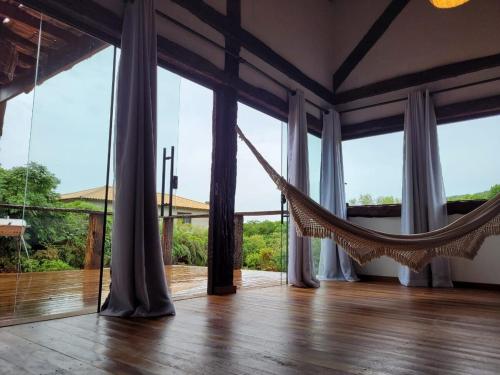 a hammock in a room with large windows at Vila Santiago - Chalé Quaresmeira in Santana do Riacho