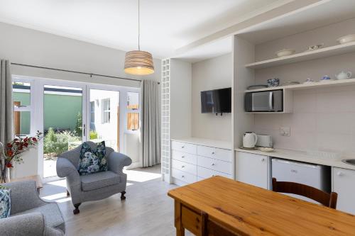 a kitchen and living room with a table and a chair at Twelve on Arum in Somerset West