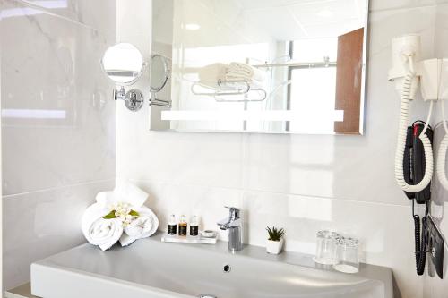 a white bathroom with a sink and a mirror at Best Western Tbilisi City Center in Tbilisi City
