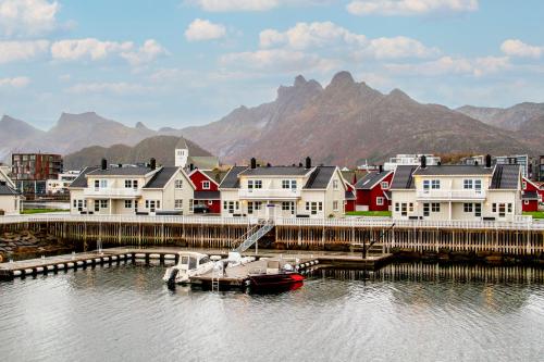 a marina with houses and a boat in the water at Svolvær Havn Waterfront Villa in Svolvær
