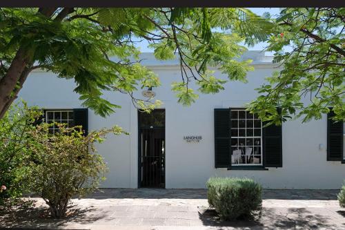 a white house with black shutters and a door at Langhuis Guesthouse in Graaff-Reinet