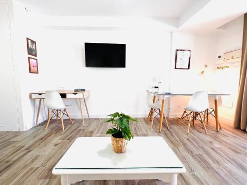 a living room with a white table and a tv at Prime garden-view Studios in Arona