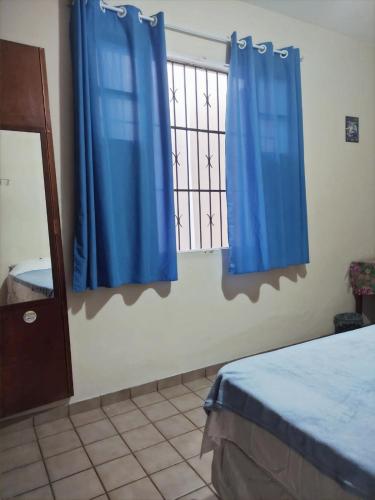 a bedroom with blue curtains and a window at Casa Monjardim in Vitória