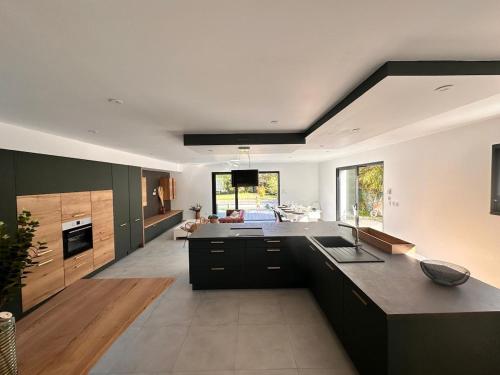 une grande cuisine avec des armoires noires et un salon dans l'établissement Villa avec piscine aux portes des Sables d'Olonne, à Talmont-Saint-Hilaire