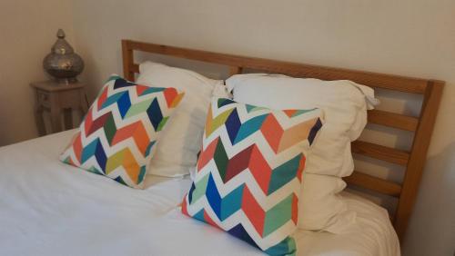 a bed with two colorful pillows on it at La Mansarde in Saint-Émilion