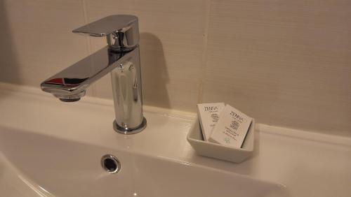 a bathroom sink with a faucet and a soap holder at La Mansarde in Saint-Émilion