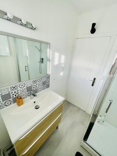 une salle de bain avec un lavabo et un miroir dans l'établissement Cosy & Spacieux 3 chambres - proche du centre et de la gare, à Besançon