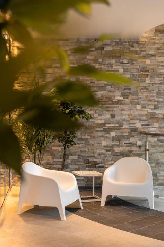 two white chairs and a table in front of a brick wall at Coco Boutique Hotel & Spa in Karpacz